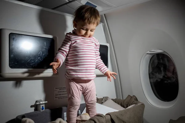 violation of safety rules in an airplane. danger. cute little toddler stand in baby bassinet during the flight