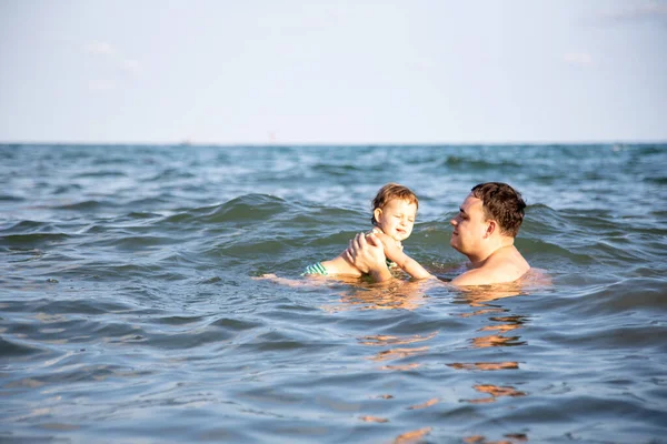 父親は概念を愛してる。最高のお父さん。父は暖かい海の水の中でかわいい幼児の娘を泳ぐことを教えています — ストック写真