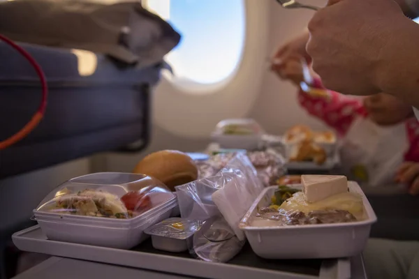 Close-up passenger plane eats tasty hot meal on board on a folding table. in the background is a window in the porthole. — Stock Photo, Image