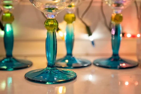 Γκρο πλαν μπλε πόδια από γυάλινα κύπελλα σε λευκό τραπέζι. γιρλάντα τρεμοπαίζει στο παρασκήνιο — Φωτογραφία Αρχείου