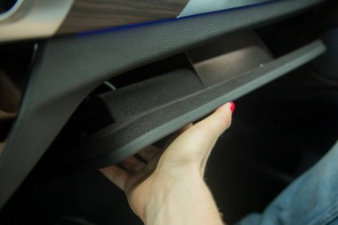 Kadınların elleri siyah bir arabanın içindeki eldiven kutusunu kapatır. yakın çekim, yumuşak odak.