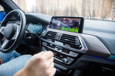 Modern teknoloji konsepti, yol yardımı. Adam, modern bir arabanın 360 adet çevre görüşlü yardım sistemini kontrol ediyor. Yakın plan, arkaplan bulanık. 