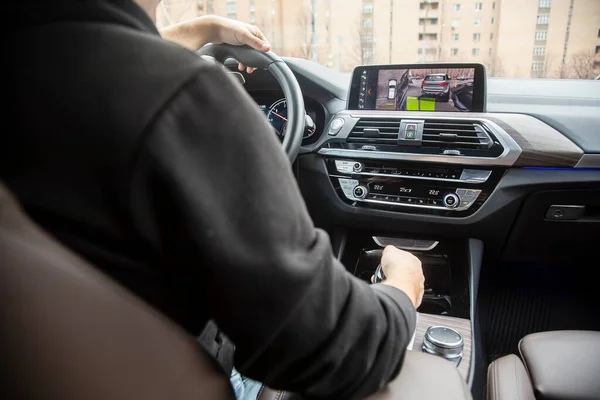 Irreconocible manis aparcamiento de nuevo utilizando la cámara envolvente asistencia de estacionamiento con radar de estacionamiento en la pantalla táctil. tecnologías modernas, seguridad de conducción y estacionamiento. Primer plano, fondo borroso . —  Fotos de Stock