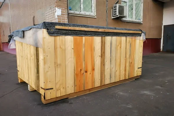 Une très grande boîte en bois se trouve dans la rue près de l'entrée d'un immeuble résidentiel. gros plan, mise au point douce, fond flou — Photo