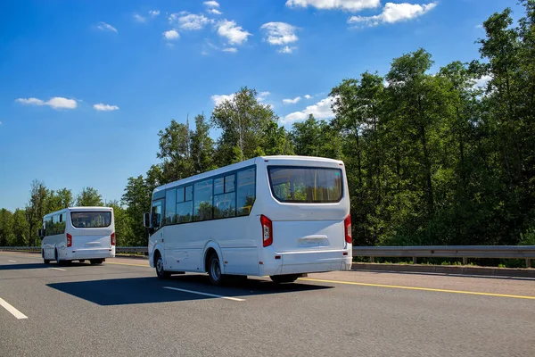 Yazın güneşli bir günde iki yeni beyaz minibüs otoban boyunca bir konvoyla gidiyor. Kapat, arka plan