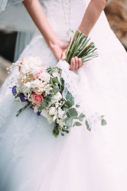 Gelinin gül buketinin yakın çekimi, okaliptüs, beyaz, kırmızı, menekşe tonları. Gelin elinde bir buket tutuyor. Gelin döndü.