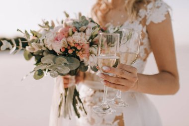 Bir buket şeftali gülü, karanfil ve okaliptüs. Beyaz elbiseli gelin elinde bir buket tutuyor ve...