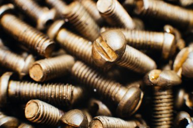 Yakın plan, makro. Eski Sovyet pirinç teneke kafa düz başlı tornavidayla vidalanıyor. Doku, vidaların arka planı. Altın renkli vidalar. Kirli tahta vidaları yağda. Pirinç hurda metal.