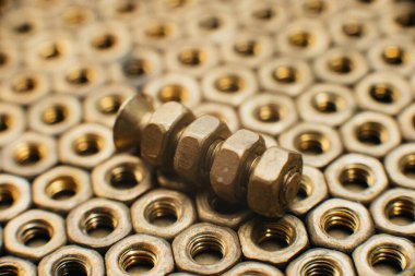 Yakın plan, makro. Eski Sovyet pirinçleri, düz başlı tornavidayla kafa vidalarını batırdı. Pirinç cevizlerinin dokusu, arkaplanı bal peteği şeklinde dizilmiş. Altın renkli vidalar. Kirli odun vidaları