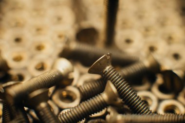 Yakın plan, makro. Eski Sovyet pirinçleri, düz başlı tornavidayla kafa vidalarını batırdı. Pirinç cevizlerinin dokusu, arkaplanı bal peteği şeklinde dizilmiş. Altın renkli vidalar. Kirli odun vidaları