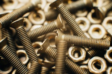 Yakın plan, makro. Eski Sovyet pirinçleri, düz başlı tornavidayla kafa vidalarını batırdı. Pirinç cevizlerinin dokusu, arkaplanı bal peteği şeklinde dizilmiş. Altın renkli vidalar. Kirli odun vidaları