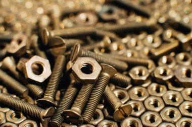 Yakın plan, makro. Eski Sovyet pirinçleri, düz başlı tornavidayla kafa vidalarını batırdı. Pirinç cevizlerinin dokusu, arkaplanı bal peteği şeklinde dizilmiş. Altın renkli vidalar. Kirli odun vidaları