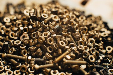 Yakın plan, makro. Eski Sovyet pirinçleri, düz başlı tornavidayla kafa vidalarını batırdı. Pirinç cevizlerinin dokusu, arkaplanı bal peteği şeklinde dizilmiş. Altın renkli vidalar. Kirli odun vidaları