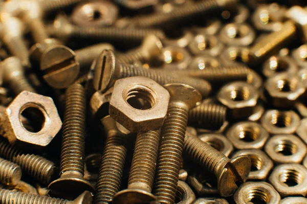 Yakın plan, makro. Eski Sovyet pirinçleri, düz başlı tornavidayla kafa vidalarını batırdı. Pirinç cevizlerinin dokusu, arkaplanı bal peteği şeklinde dizilmiş. Altın renkli vidalar. Kirli odun vidaları