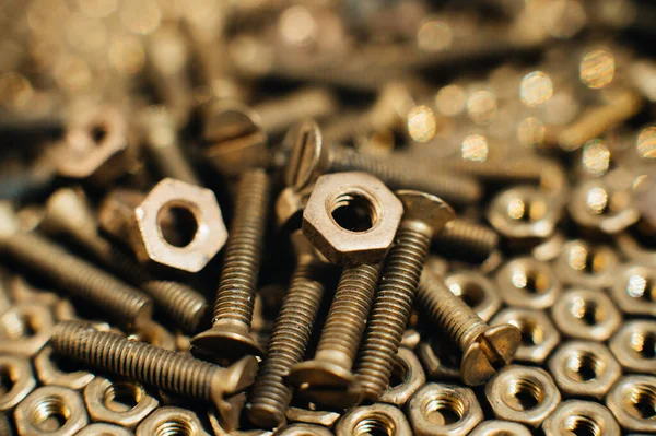 Yakın plan, makro. Eski Sovyet pirinçleri, düz başlı tornavidayla kafa vidalarını batırdı. Pirinç cevizlerinin dokusu, arkaplanı bal peteği şeklinde dizilmiş. Altın renkli vidalar. Kirli odun vidaları