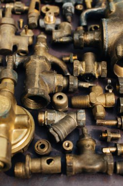 Pirinç hurda metal: musluklar, tişörtler, prizler ve çeşitli tesisat parçaları, yedek parçalar. Bakır bir yaprağın arka planına karşı. Yakın plan..