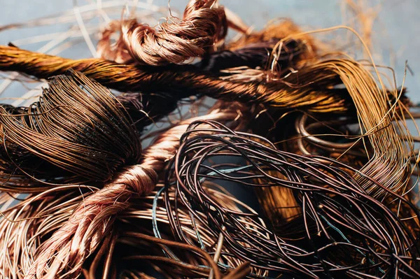 Copper scrap metal, wire, windings of motors and transformers, electrical wire without insulation. Against the background of a copper sheet. Close-up. Macro.