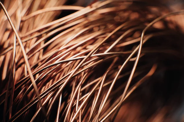 Copper scrap metal, wire, windings of motors and transformers, electrical wire without insulation. Against the background of a copper sheet. Close-up. Macro.