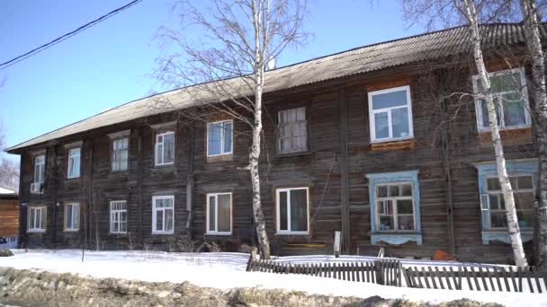 Stary drewniany, dwupiętrowy budynek mieszkalny. Chmurny dzień, zima. Rosja, Syberia. Khanty-Mansi Autonomiczny Okrug-Yugra — Wideo stockowe