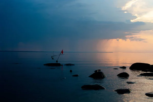 a sunset on the baltic sea with orange flag and stones