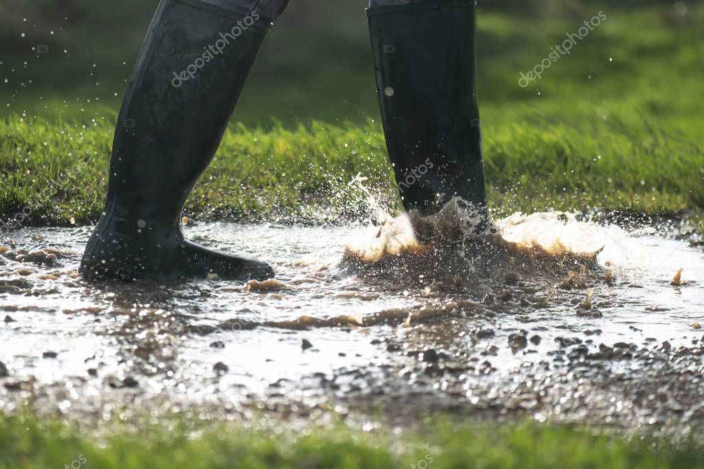 person in boots walking in wet muddy puddles