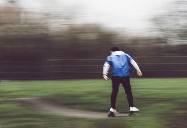 Arka planda, kaykaylı kaykayla kaykay yapan ve kaykay parkında gösteri yapan tanınmamış bir adam var.