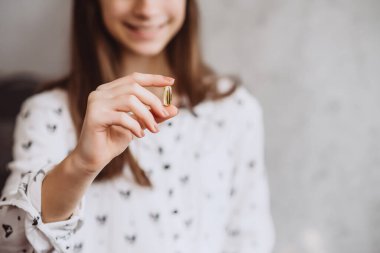 Diyet olsun. Beslenmek. Morina karaciğeri omega-3 yağıyla hap alan bir kız. Sağlıklı beslenme ve yaşam tarzı kavramı. D vitamini, E vitamini, balık yağı kapsülleri..