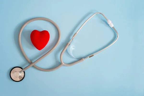 Stethoscope and red heart on a blue background. Cardiology and heart health concept. The medicine. Selective focus. Copy space.