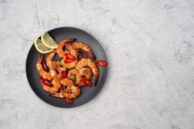 Gri beton arka planda acı biberli ve limonlu lezzetli kızarmış karides. Sağlıklı deniz ürünleri. Uzayı kopyala Düz yatıyordu.