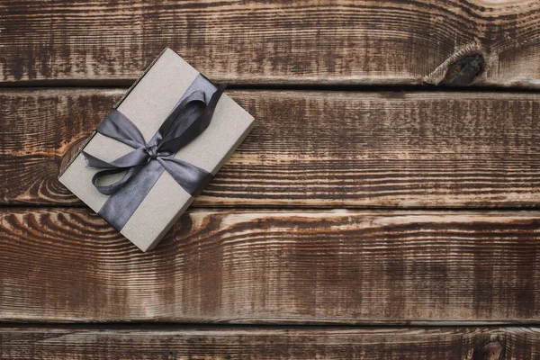 Gift craft box with beige ribbon on a wooden background. Father\'s day. Gift for a man. Flat lay.