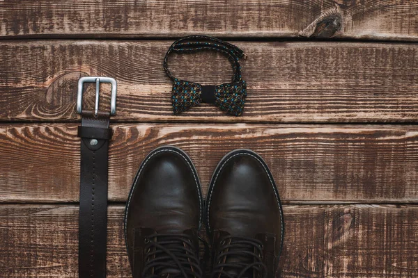 father's day with men's accessories belt and bow tie and leather shoes on a wooden background. Copy space. Flat lay.