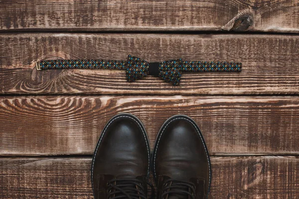 men\'s accessories bow tie and leather shoes on a wooden background. Copy space. Flat lay.