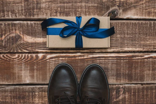木製の背景に青いリボンと男性の革の靴とギフトボックス 父の日だ 男への贈り物だ — ストック写真