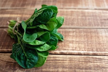 Temiz gıda konsepti. Tahta zemin üzerinde taze taze toplanmış taze taze organik ıspanak yaprakları. Sağlıklı bahar-yaz diyeti. Vegan Çiğ Gıda. Boşluğu kopyala.