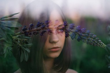 Mor lup çiçekli güzel bir kızı iki kez görmüş. Sanat fotoğrafı. Yumuşak odaklanma. Yakın plan portre. Güzel gözler..