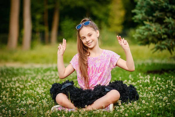 Piękna Dziewczynka Długim Ogonem Włosów Pełnej Spódnicy Siedzi Trawie Rękami — Zdjęcie stockowe