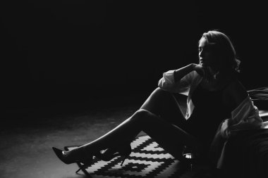 Yatak odasında yalnız ve güzel bir kadın bir bardak şarapla yatakta dinleniyor. Alçak bir tonda siyah beyaz resim. Yumuşak seçici odak.