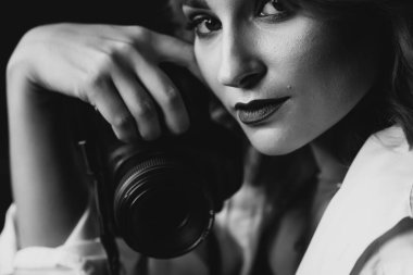Elinde fotoğraf makinesi olan güzel bir kadın fotoğrafçının portresi. Siyah beyaz resim. Yumuşak seçici odak.