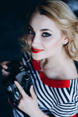 Fotoğraf stüdyosunda elinde kamerayla genç ve güzel bir fotoğrafçı kız. Kadın işi bir hobidir. Yumuşak seçici odaklanma. Renkli fotoğraf.