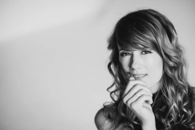 36 yaşında kıvırcık saçlı ve kahverengi gözlü bir kadının portresi. Yumuşak seçici odaklanma. Siyah beyaz sanat fotoğrafı..