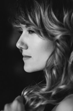 36 yaşında kıvırcık saçlı ve kahverengi gözlü bir kadının portresi. Yumuşak seçici odaklanma. Siyah beyaz sanat fotoğrafı..