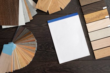 Ev tasarımı konsepti. Müşteriler için doğal ahşap malzeme numunesi. Laminat ve vinil döşeme paleti ve çizimler için boş defter. İnşaat ve onarım.