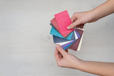 Tasarımcının elinde hakiki deriden yapılmış renkli moda örnekleri, modern mağazalar, endüstri konsepti. Renkli deri örnekleriyle dolu palet kataloğu. Kapak tasarımı.