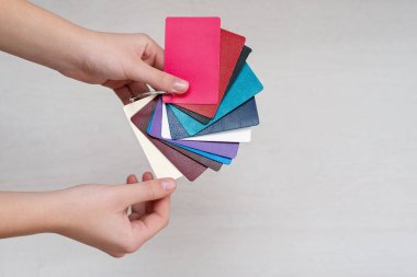 Tasarımcının elinde hakiki deriden yapılmış renkli moda örnekleri, modern mağazalar, endüstri konsepti. Renkli deri örnekleriyle dolu palet kataloğu. Kapak tasarımı.
