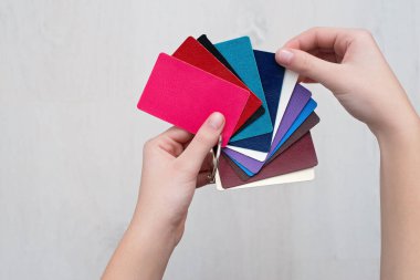 Tasarımcının elinde hakiki deriden yapılmış renkli moda örnekleri, modern mağazalar, endüstri konsepti. Renkli deri örnekleriyle dolu palet kataloğu. Kapak tasarımı.