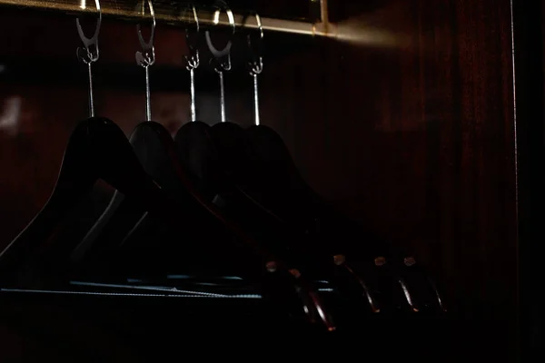 Wooden clothes hanger. Many wooden black hangers on a bar. Concept store, sale, design, empty hangers. Soft selective focus.