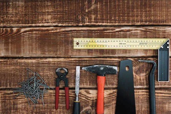 Stock image Collection of woodworking tools on a wooden background and copy space: carpentry, craftsmanship and handmade concept, flat lay. Saw, hammer, chisel, nails, ruler.