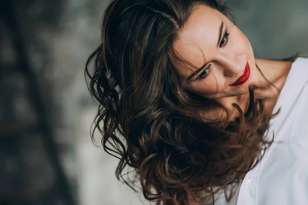 完璧な暗い巻き毛と白いシャツのぽっちゃり赤い唇と美しい化粧を持つ美しい若い女性 柔らかい選択的フォーカス — ストック写真
