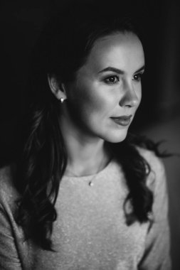 Koyu renk kıvırcık saçlı, kahverengi gözlü, tavan arasında altın rengi bir elbise giyen güzel, koyu tenli bir kadın. Profilde yakın plan portresi var. Yumuşak seçici odaklanma. Siyah beyaz fotoğraf.