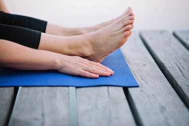 Kadın, sabahları tahta bir iskelede, nehrin kenarında yoga yapıyor. Sağlıklı yaşam tarzı kavramı. Sabah meditasyonu, rahatlama.